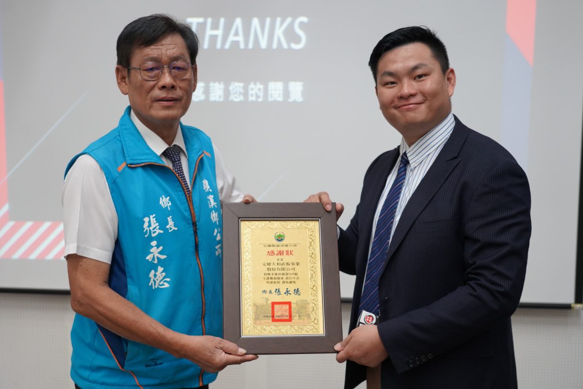 元健天籟列車宜蘭縣礁溪站啟動合影,身穿藍色鄉長背心的長者與深色西裝男士在THANKS投影畫面前合捧感謝狀,點擊閱讀〈元健天籟列車》宜蘭縣礁溪站啟動!〉