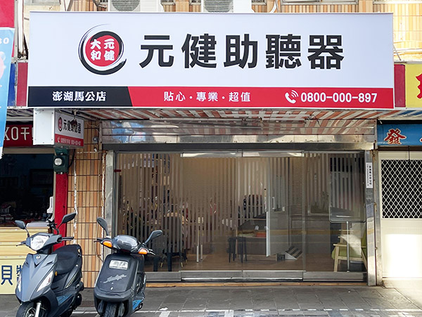 元健助聽器澎湖馬公店門市外觀，白色招牌印有元健助聽器標誌、澎湖馬公店、貼心專業超值與免付費專線0800-000-897，入口為玻璃門，門前停放兩輛機車。