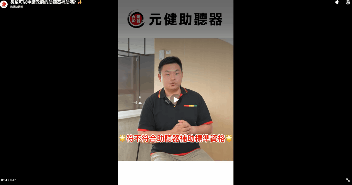 元健助聽器直式影片截圖：身穿黑色Polo衫的元健助聽器人員在門市內雙手交握講解，畫面字幕寫著「符不符合助聽器補助標準資格」，點擊觀看〈長輩可以申請政府的助聽器補助嗎?〉